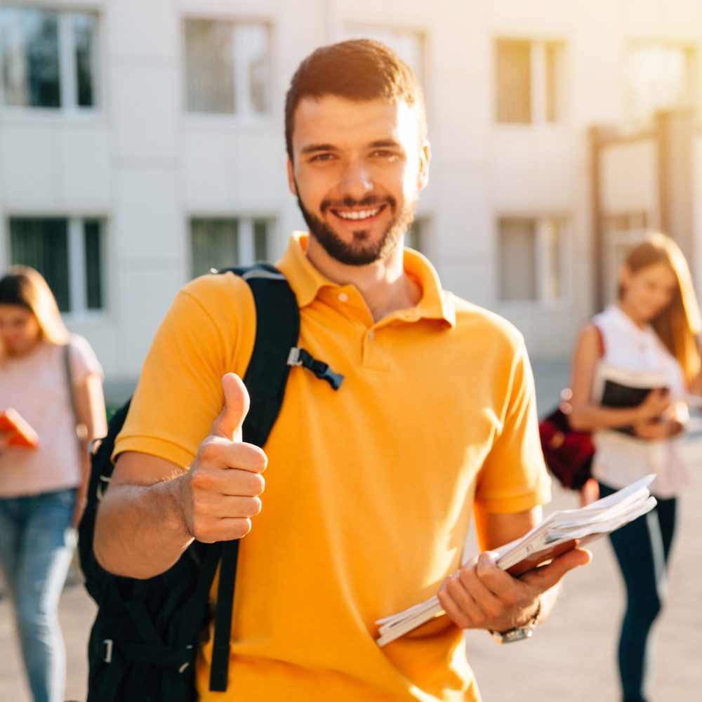 young-attractive-smiling-student-showing-thumb-up-outdoors-campus-university